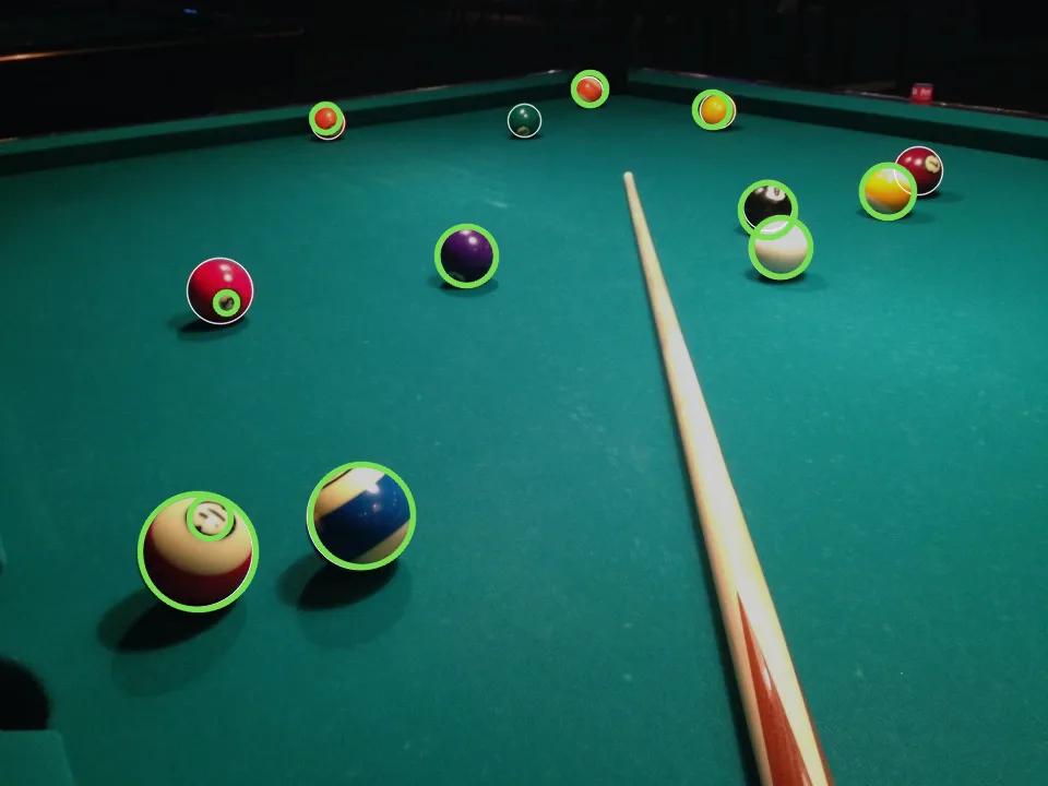 A close view of a pool table with green circles on most balls, white circles on the labelled balls, and one small green circle inside the big ball in front, on its printed number