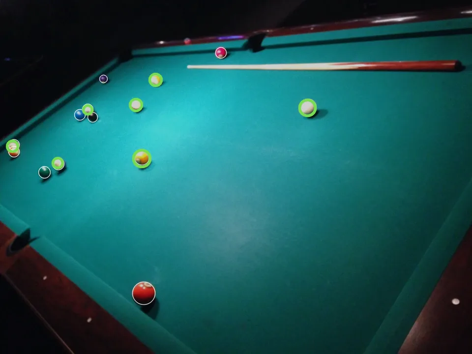 A wide view of the whole pool table with green circles on seven balls, and thin white outlines alone on the small far balls it missed