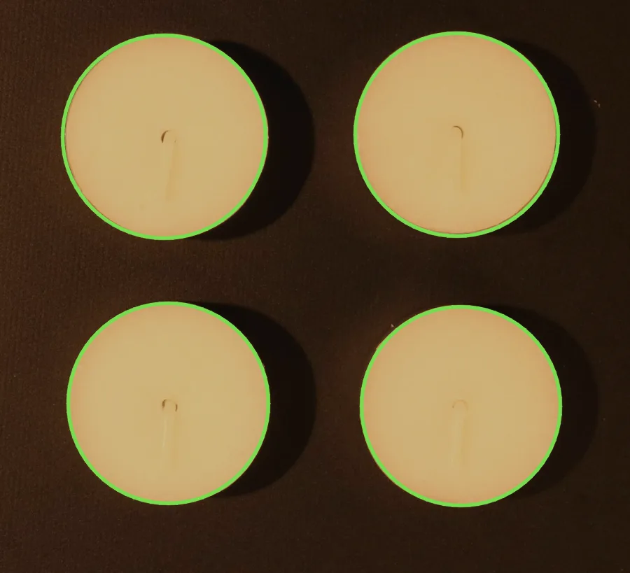 Four tea lights on a dark background seen from above, each ringed by a green circle