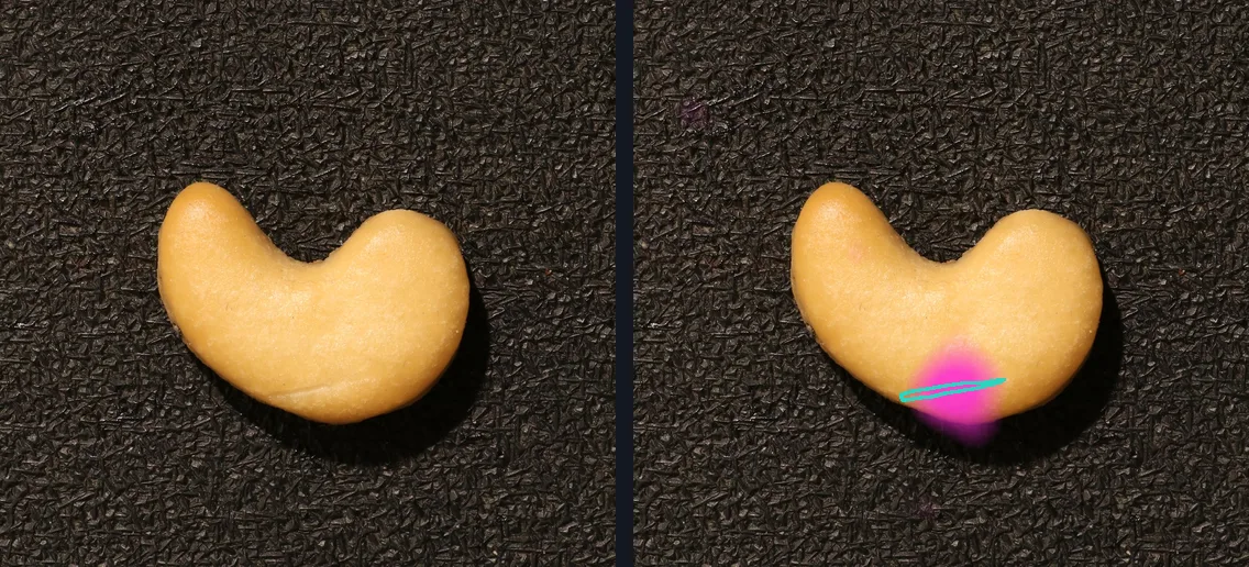 A cashew nut on a dark textured background, shown twice. On the right a magenta heat overlay is brightest along a thin scratch near the bottom edge of the nut, which is outlined in teal.