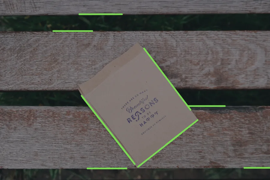 A sheet of paper on a wooden bench at an angle, with green segments along its long sides and one short side