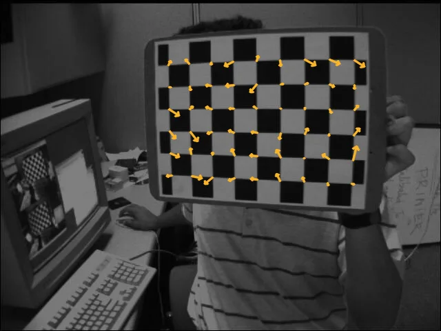 The first chessboard photo with a small amber arrow at each inner corner pointing from the detected corner toward the predicted one; the arrows are short and point in no common direction